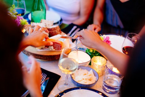 Women share cheese plate at outdoor dinner party